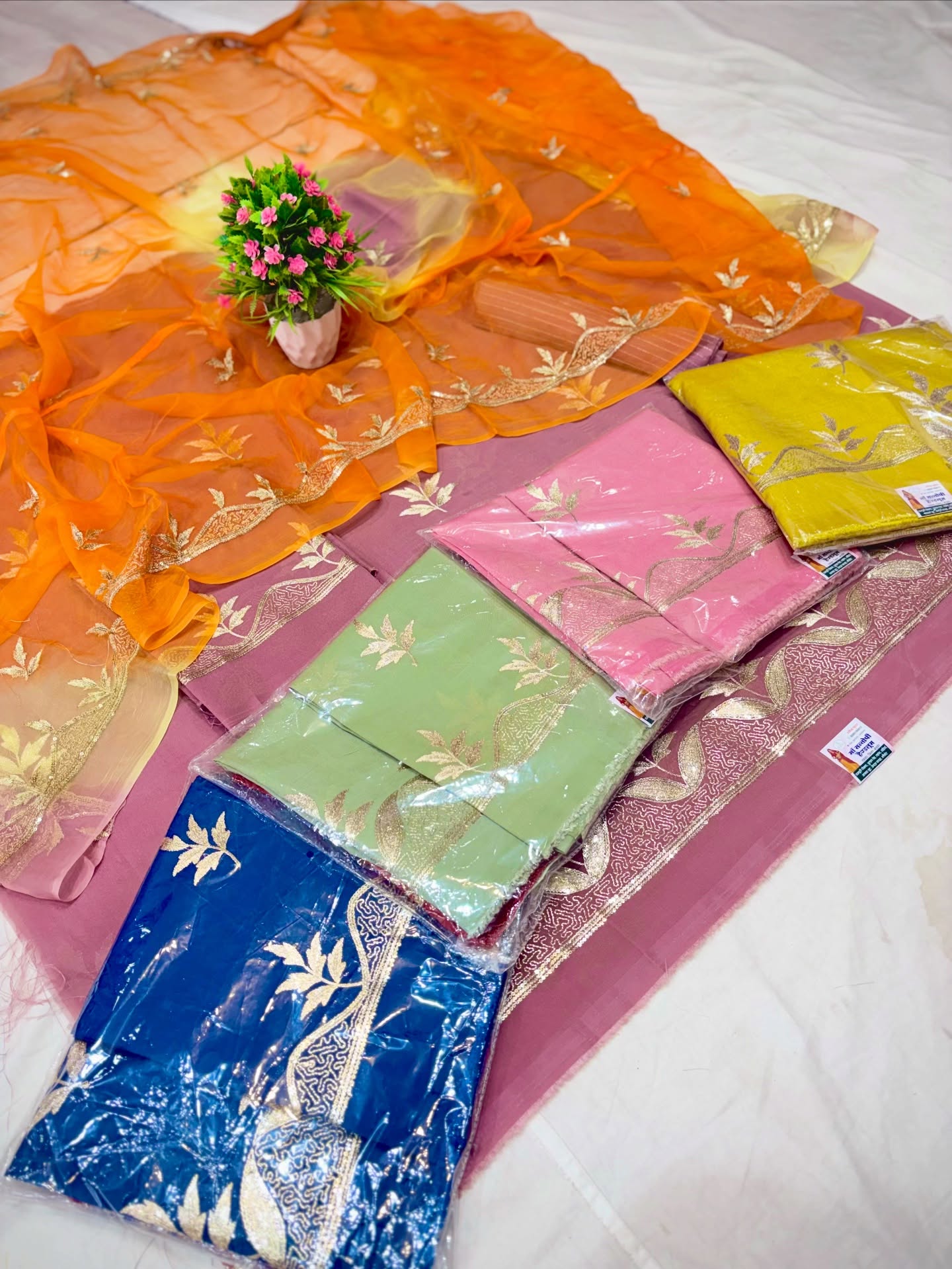 A vibrant collection of multicolor traditional Indian dress materials and saree sets featuring rich fabrics, festive designs, and assorted patterns.